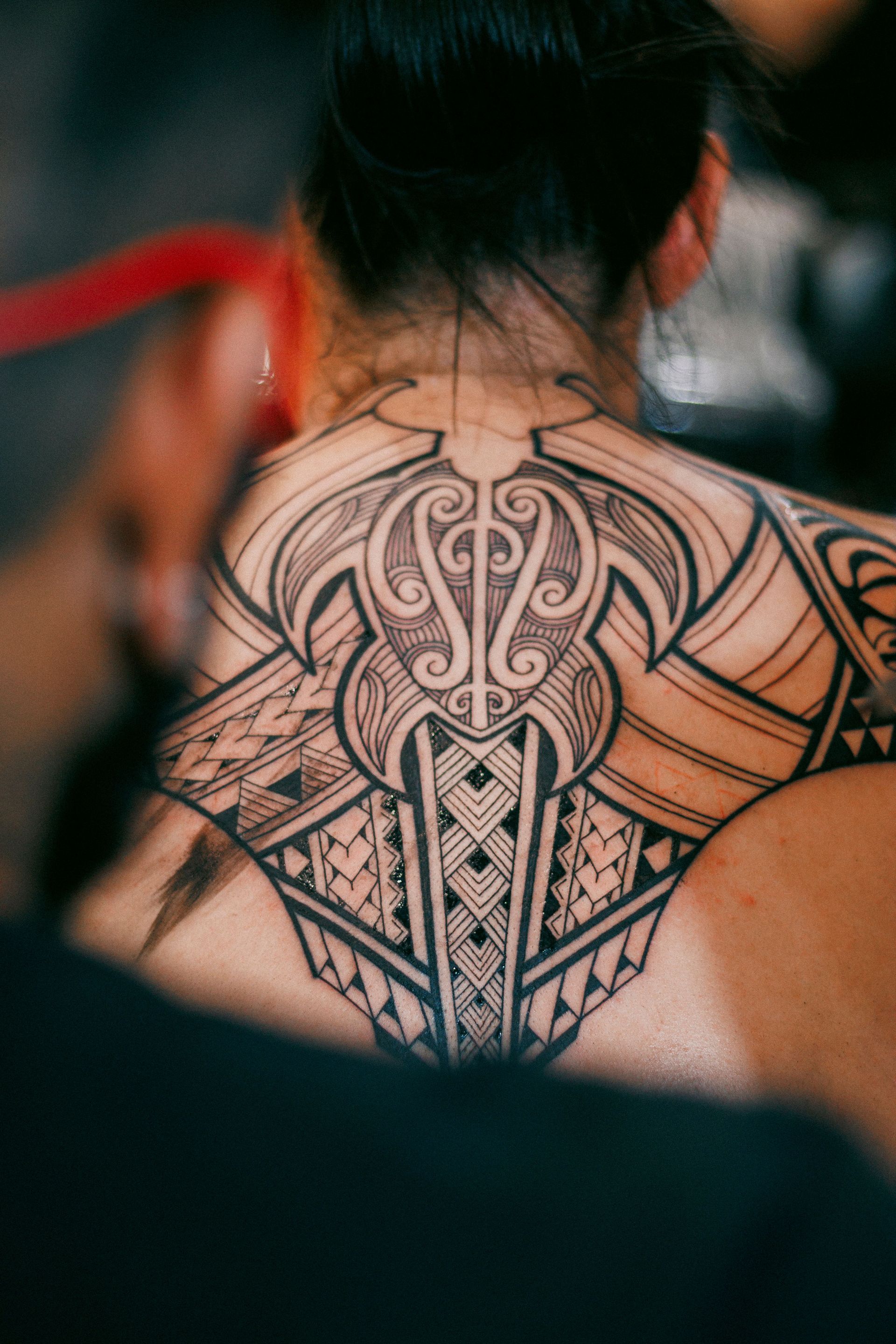 Detailed black ink tribal tattoo on a person's back, showcasing artistry.