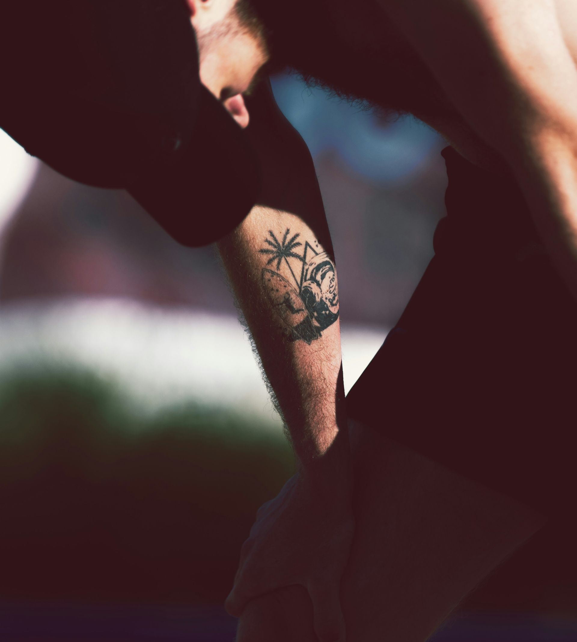 Man with palm tree tattoo bends over