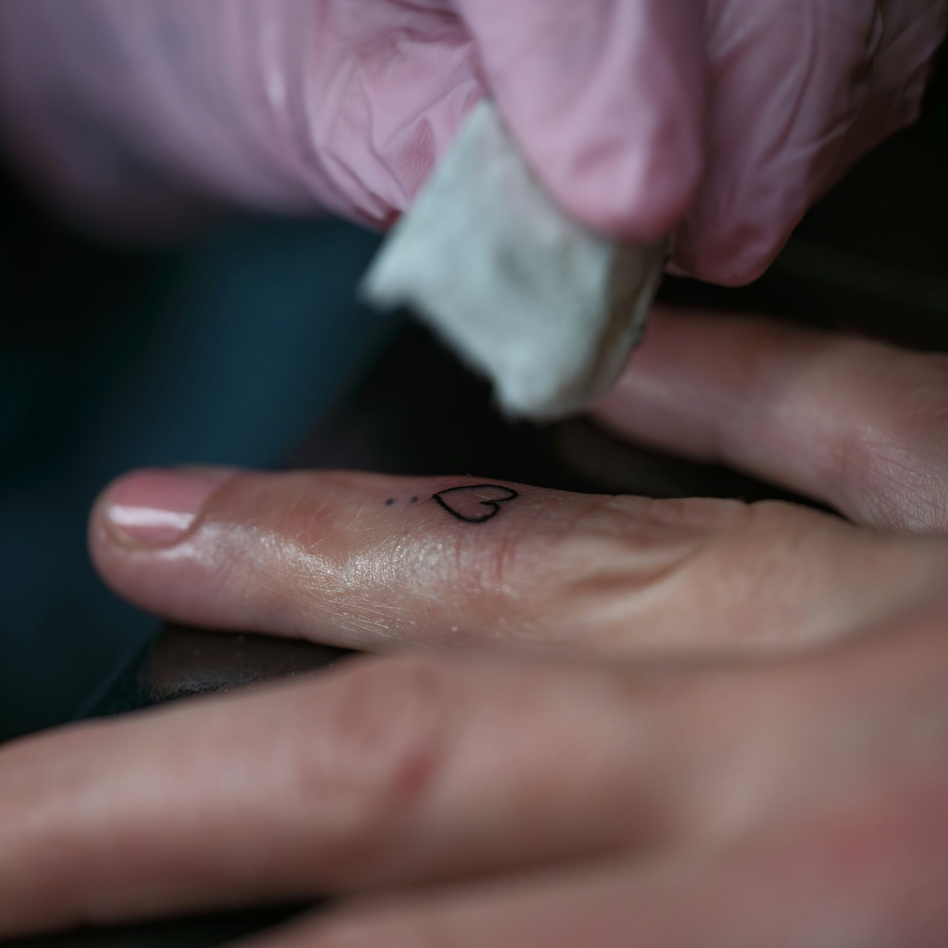 A person with a small heart tattoo on their finger